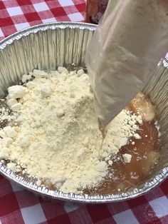 a metal pan filled with food on top of a red and white checkered table cloth