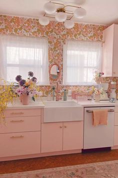 a kitchen with pink cabinets and floral wallpaper on the walls, along with a white dishwasher