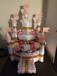 a large cake with pink and gold decorations on it's sides, sitting on a table