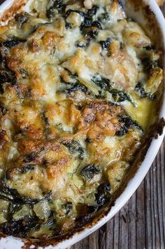 a casserole dish with spinach and chicken in it on a wooden table