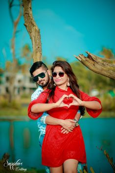 a man and woman standing next to each other with their hands in the shape of a heart