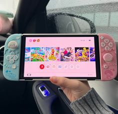 a person holding up a nintendo wii game controller in their hand while sitting in a car