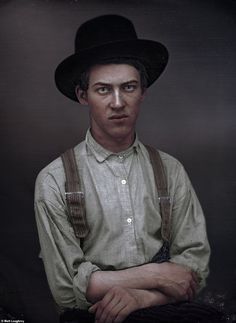 a man with suspenders and a hat is looking at the camera while posing for a portrait