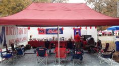 a red and white tent is set up with chairs under it for an outdoor event