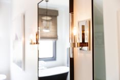 a bathroom with a sink, mirror and bathtub in the background is seen through an open door