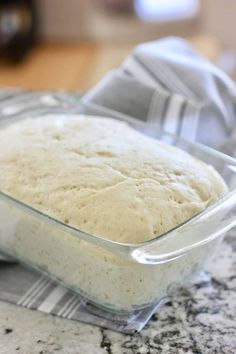 a loaf of bread sitting in a glass dish on top of a marble countertop