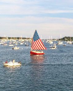 several small boats floating in the water with an american flag on one side and another boat behind them