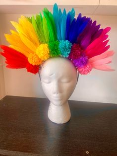 a white mannequin head with multi colored feathers on it