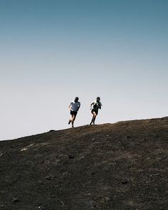 two people running up a hill on a clear day