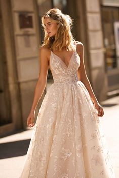 a woman in a wedding dress is walking down the street with her hand on her hip