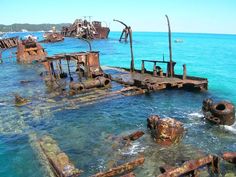 an old rusted out ship in the ocean with water around it and several other rusty ships