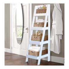 a white ladder shelf with baskets and towels on it in front of a mirror next to a door