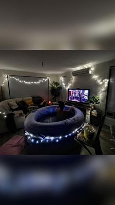 an inflatable hot tub is lit up with fairy lights and the tv is on