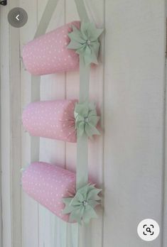 three pink pillows hanging on the side of a white door with green ribbons and bows