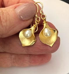 Shop Calla Lily Earrings Gold. Real pearl earrings will add a perfect touch of flair to your outfit!  You can wear it with your evening dress or favorite jeans.  These flower earrings are made from: -Gold plated calla lily flowers (18mm x 13mm)  -White freshwater pearls -Gold filled ear wires Pearl drop dangle earrings are 1.25" long.  It will make a great bridesmaid gift or flower girl gift.  Back to my shop: https://www.etsy.com/shop/jewelrybyirina Your order of bohemian jewelry will be mailed within 2 business days via USPS. US orders and most international orders will have a tracking#. Thank you for visiting Gold Bridesmaid Earrings, Lily Earrings, Calla Lily Flowers, Real Pearl Earrings, Bridesmaid Earrings Gold, Lily Flowers, Flower Girl Gifts, Jewelry Birthday, White Freshwater Pearl