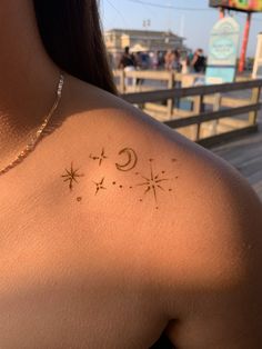 the back of a woman's shoulder with stars and a crescent tattoo on it