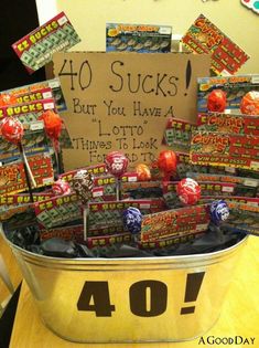 a bucket filled with lots of candy sitting on top of a wooden table next to a sign that says 40 sucks but you have a lot of them