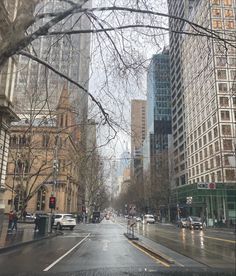 an empty city street with tall buildings on both sides and trees in the foreground