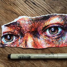 a pencil is laying on top of a piece of paper with an image of a person's eyes