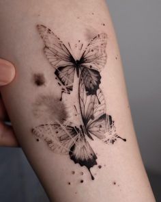 a black and white butterfly tattoo on the right arm, with watercolors all over it