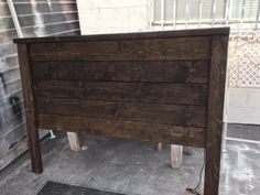 a wooden bed frame sitting on top of a sidewalk