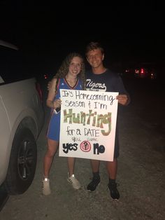 two people standing next to each other holding a sign that says hunting for a date