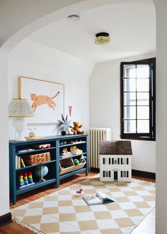 a child's playroom with toys, bookshelf and toy house on the floor