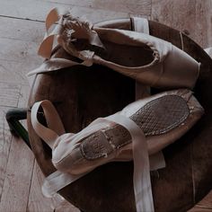 two pairs of ballet shoes sitting on top of a wooden table