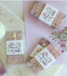 four small pink and white boxes with flowers on them sitting next to each other in front of a flower bouquet