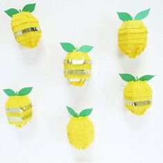 four pieces of paper are arranged in the shape of yellow fruit with green leaves on them