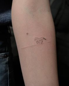 a person with a small tattoo on their arm that has a horse running in the distance