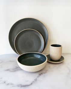 a marble table topped with two plates and cups next to each other on top of a white counter