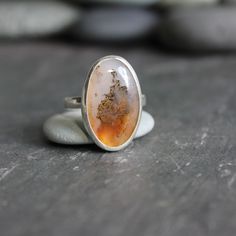 Handmade Sterling Silver Oregon Graveyard Point Plume Agate Statement RingPlume agates are thought to eliminate and transform negativity...Who knew? It is also just a really pretty earthy gemstone...found in Oregon, cut in Oregon and made in Oregon! Here are the details:* This Oregon Graveyard Point round plume agate ring is made with a locally-sourced & cut cabochon...set in fine & sterling silver on a sturdy silver band - handcrafted by Will Macy. Size 10 3/4 Handmade Oval Moss Agate Ring, Agate Gemstone Rings In Oval Cabochon, Agate Gemstone Rings In Oval Cabochon Shape, Oval Agate Ring With Large Stone, Bohemian Oval Agate Rings, Oval Agate Rings For Healing, Oval Amber Agate Ring, Amber Oval Agate Ring, Nature-inspired Untreated Oval Rings