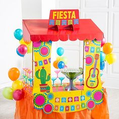 there is a fiesta stand with balloons and confetti on the table in front of it