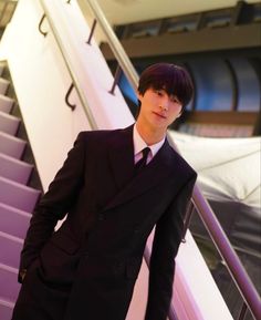 a man in a suit and tie standing next to an escalator with his hands on his hips