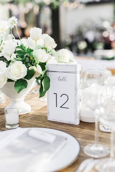 the table is set with white flowers and place cards