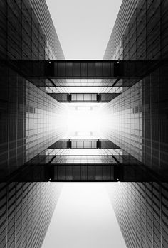 looking up at the sky from between two skyscrapers in black and white, as seen from below