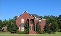 a red brick house surrounded by trees and grass