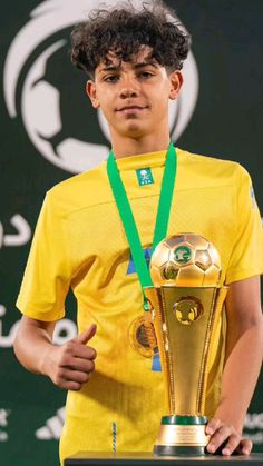 a young man holding a soccer ball and trophy