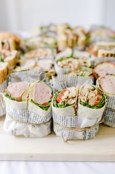 sandwiches wrapped in newspaper sitting on top of a table