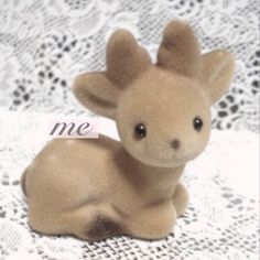 a small stuffed animal sitting on top of a lace covered table cloth with the word me written across it