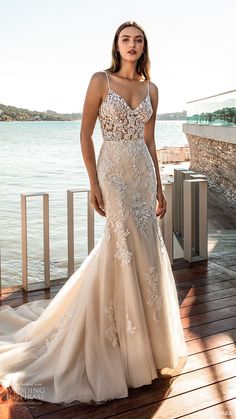 a woman in a wedding dress standing on a deck near the water with her hands on her hips