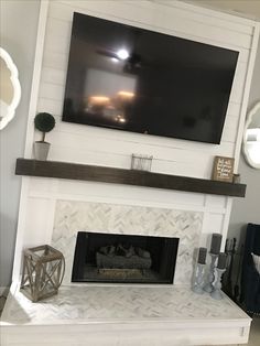 a white fireplace with a flat screen tv above it and candles on the mantel