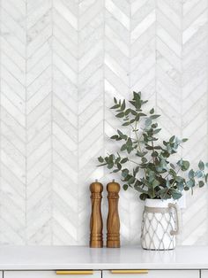 white marble herringbone wallpaper with wooden handles and plant in vase on countertop