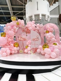 pink and gold balloons are on display in front of a castle with a sign that says flamingo