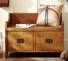 a wooden bench with two drawers and a bike pillow on the top, in front of a window