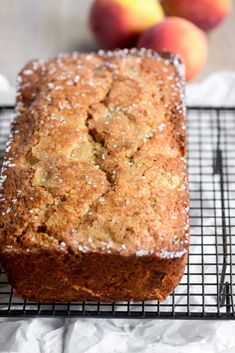 a loaf of bread sitting on top of a cooling rack next to some peaches