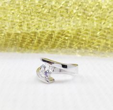 a diamond ring sitting on top of a table next to a yellow background with glitter