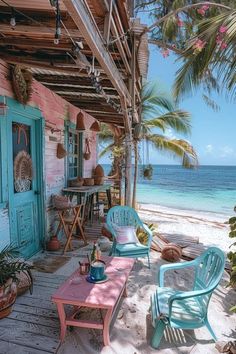 two chairs and a table on a porch next to the ocean with palm trees in the background