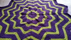 a purple and green crocheted blanket on the floor